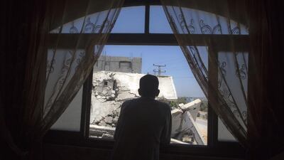 Beit Hanoun resident Ramzi Hassouna,41, stands in the living room of his home as he looks out of the window overlooking the ruins of his neighbor's home, destroyed in an Israeli attack last summer. (Photo by Heidi Levine for The National ).