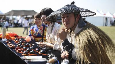 Korean falconers look at falcon hoods on display.
