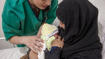 A midwife guides Naeema through the breastfeeding process with her baby