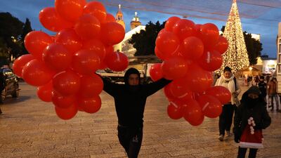 A street vendor selling festive balloons at Manger Square, next to the Church of the Nativity. The church is administered jointly by the Greek Orthodox, Roman Catholic, Armenian Apostolic, and Syriac Orthodox churches. EPA
