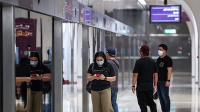 Mask-clad passengers stand along the train platform at a station in Doha, Qatar. AFP