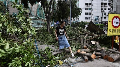 A woman steps over a fallen tree on a pavement in Macau on August 24, 2017. The death toll from Severe Typhoon Hato rose to at least 16 after the storm left a trail of destruction across southern China, blacking out Macau's mega-casinos and battering Hong Kong's skyscrapers. Anthony Wallace / AFP
