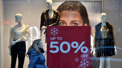 A woman walks past a poster announcing 50 percent sale is seen at the window display of a shop in Beirut, Lebanon. EPA