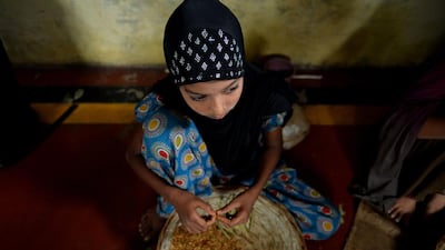 Twelve year old Indian villager Tarannum Alvi sits with materials as she tries to roll bidi's in Kannauj.