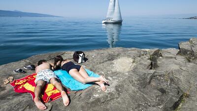 A couple sunbathing by Lake Geneva in Saint-Saphorin, Switzerland. Dominic Steinmann/EPA