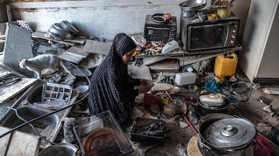 A Palestinian woman and a cat sit in a ruined kitchen in a home in Beit Hanoun, northern Gaza, on May 22, 2021. Getty