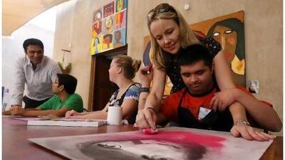 Sonja Tatton helps Umer Shuja, 22, with an artwork at the studio in Dubai.