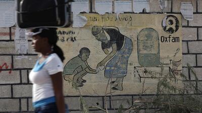 A woman walks past an Oxfam sign in Corail, a camp for displaced people of the 2010 earthquake, on the outskirts of Port-au-Prince, Haiti / Reuters