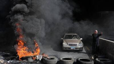 A Maronite priest pleads with anti-government protesters to let him pass with his vehicle as he stands next to burning tyres at a makeshift roadblock in Zouk Mosbeh, north of Lebanon's capital Beirut. AFP