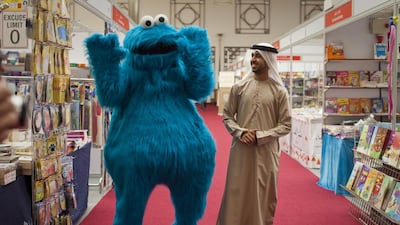 The creative director of the new version of Iftah Ya Sim Sim, Abdalla Al Sharhan, with the Sesame Street muppet Cookie Monster, known as Kaaki in the Arab version, at the Al Ain Reads Bookshow. Razan Alzayani / The National