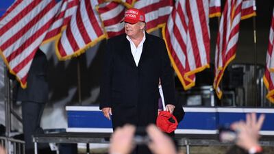 Former US president Donald Trump holds his signature 'Make America Great Again' hats to give to his supporters in Arizona. AFP