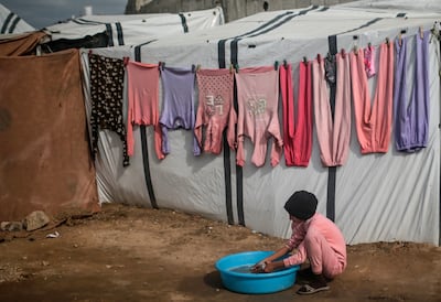 A displaced Palestinian girl hand-washes clothes outside a makeshift tent in Deir Al Balah on Wednesday. EPA