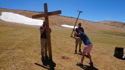 Men dig a hole to plant a cross in the ground for the mass.