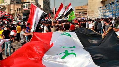 Protesters hold Iraqi flags in Tahrir Square during a demonstration this month calling for the government to resign, in Baghdad, Iraq. AP