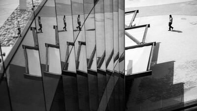 A man is reflected in the glass walls of a building on Al Maryah Island, Abu Dhabi. Brian Kerrigan / The National