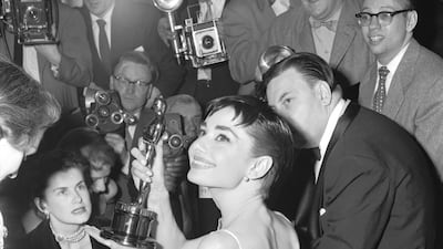 Audrey Hepburn, surrounded by photographers and reporters, holds up the Best Actress Oscar she won for her first US film Roman Holiday, at the 1954 Academy Awards. Getty Images