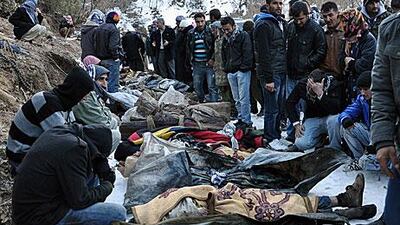 Kurds look over the bodies of those killed by a Turkish air raid on the Iraq border. Officials say that they were smugglers mistaken as PKK militants.
