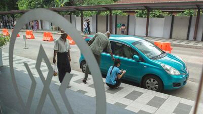 A private insurance company worker inspects a vehicle for insurance coverage outside the company's office in Yangon. Romeo Gacad / AFP