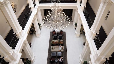 A chandelier hangs above people sitting in a lobby of the Raffles Hotel. Bloomberg