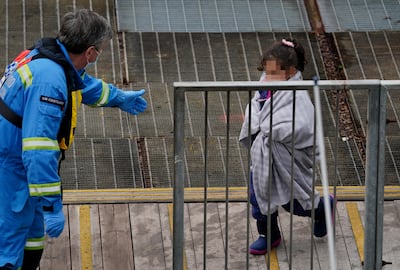 A girl who was among a group of migrants who crossed the English Channel is helped by a British coastguard officer. PA