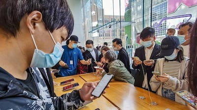 People try out the new iPhone 12 mobile phones at an Apple store in Shanghai on October 23, 2020. (Photo by STR / AFP) / China OUT
