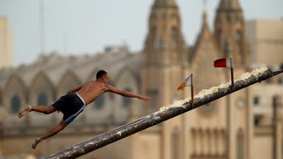 A competitor tries to grab a flag on the 'gostra', a pole covered in lard, as he falls off it during the celebrations for the religious feast of St Julian, patron of the town of St Julian's, Malta. Darrin Zammit Lupi / Reuters