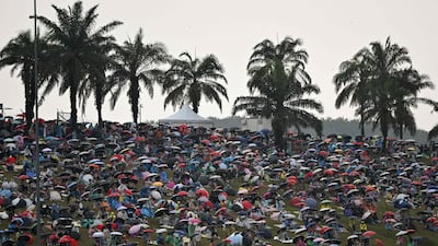Spectators shelter under umbrellas as rain delays the start of the race in Sepang. AFP