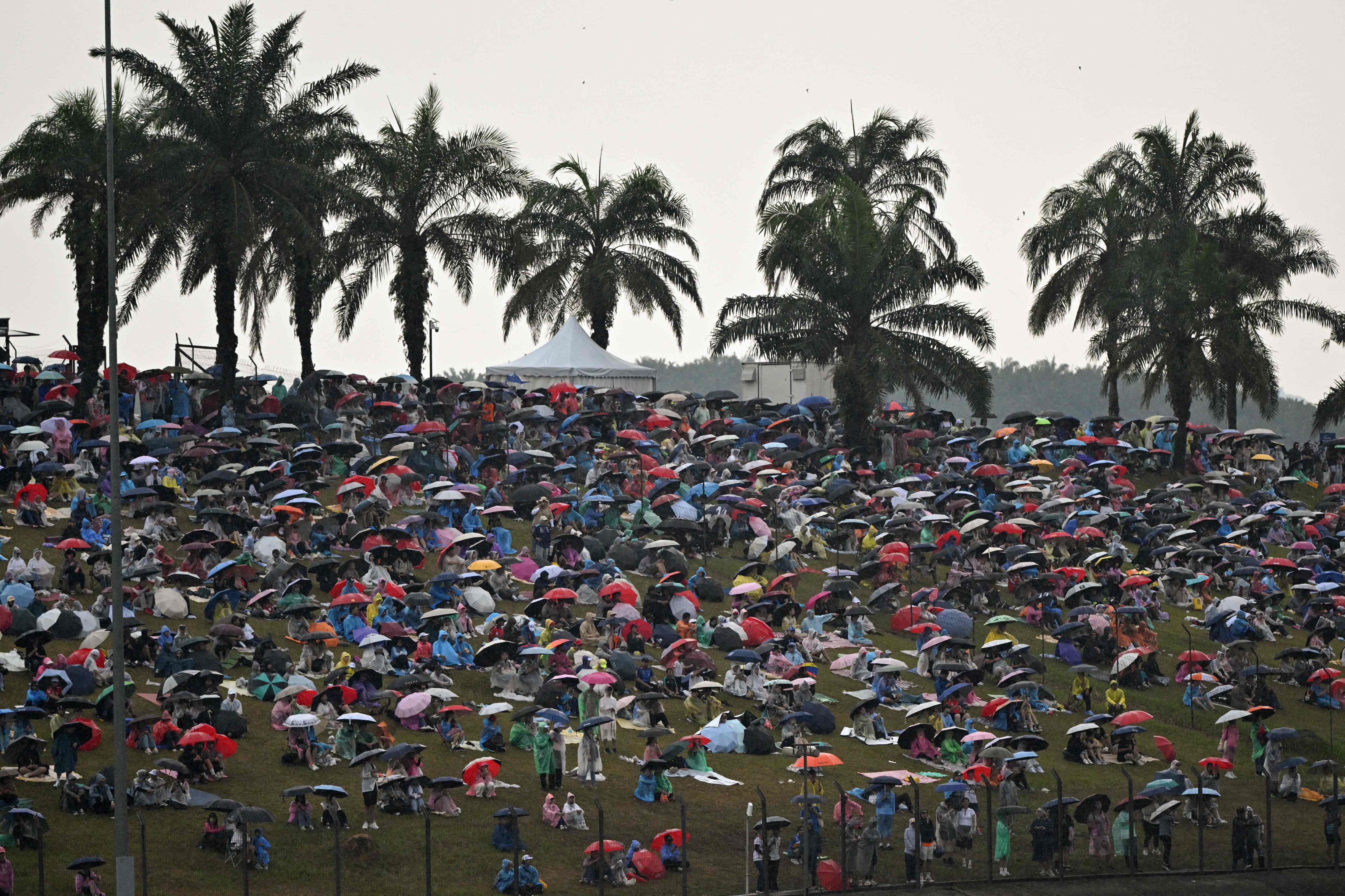 Spectators shelter under umbrellas as rain delays the start of the race in Sepang. AFP
