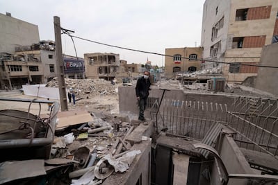 People look at the debris of destroyed buildings following a military strike on the Iranian capital Tehran on March 15, 2026. AFP