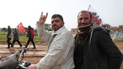 In this file photo taken on February 14, 2020, a motorcycle rider flashes the Grey Wolves gesture as people behind him march with Turkish flags during a demonstration at a Turkish military observation post in the town of Binnish in Syria’s north-western province of Idlib, near the Syria-Turkey border. AFP