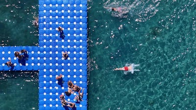 People dive from an artificial pier into the sea in Durres, western Albania. AFP