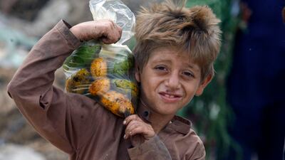 An Afghan refugee boy carries a bag of mangoes on his shoulder in Karachi, Pakistan. AP