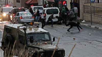 Palestinians throw stones at an Israeli army vehicle in Nablus on December 21. AFP