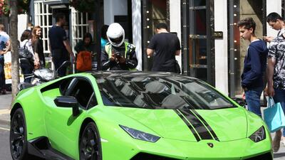 A parking attendant in Knightsbridge, London, issues a ticket to the owner of an illegally parked Lamborghini. Stephen Lock / The National