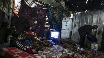 A Palestinian man removes a basin filled with water from a leaking roof inside his family tent made of tin and nylon sheets, as children huddle in a corner to watch television, on a rainy day in al-Amal (hope in Arabic) neighbourhood of Beit Lahia in the northern Gaza Strip. AFP