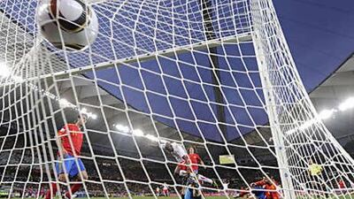 Switzerland's Gelson Fernandes, in white, scores as Spain's goalkeeper, Iker Casillas, sprawls on the ground in front of him.