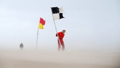 A lifeguard contends with strong wind on Portstewart Strand as she plants a warning flag advising swimmers against entering the water, in Portstewart, Northern Ireland. Getty Images