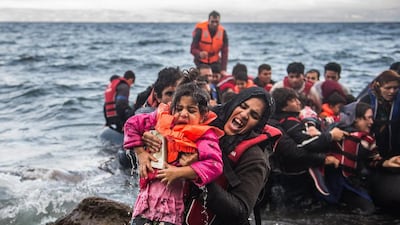 Migrants make land from an overloaded rubber dinghy as they arrive on the coast near Skala Sikaminias, Lesbos island, Greece. An estimated 100,000 refugees and migrants arrived on the Greek islands during August, according to the Hellenic Coast Guard. Filip Singer / EPA