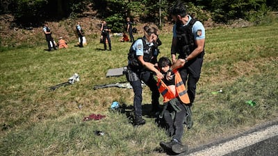French gendarmes remove environmental protestors from the race route. AFP