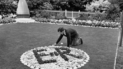 A gardener putting the finishing touches to an ER II emblem in 1953