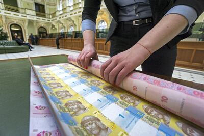 A bank worker rolls up uncut sheets of ten and one hryvnia banknotes at National Bank of Ukraine in Kiev. The currency was the world’s best-performer in 2019 out of more than 130 tracked by Bloomberg. Bloomberg