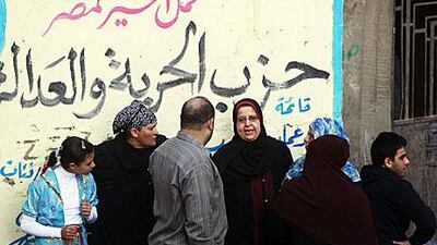 People gather outside a polling station beside an electoral slogan for the Muslim Brotherhood's Freedom and Justice Party that reads "We bring good to Egypt" in Toukh, El Kalubia governorate, northeast of Cairo on Tuesday.