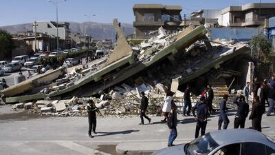 People gather around a levelled building in the mountainous town of Darbandikhan in Iraqi Kurdistan on November 13, 2017, following a 7.3-magnitude quake that hit the Iraq-Iran border area. Shwan Mohammed / AFP