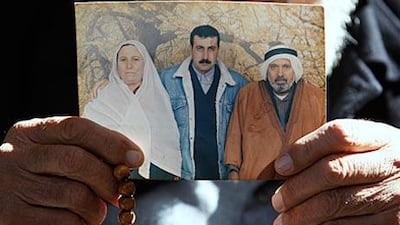 The father of Mahmoud al Mabhouh holds up a family photo showing al Mabhouh, centre, at their home in the Jebaliya refugee camp, northern Gaza.