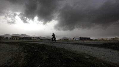 A man cycles down the street whilst a cloudy sky threatens rain in Kalba city, Sharjah. Pawan Singh / The National