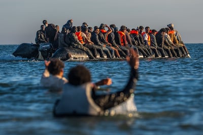 Migrants try to booard a crowded dinghy in the English Channel off northern France. Getty