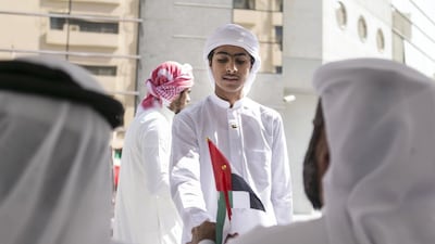 Obeid Al Katbi, 15, from Muath bin Jabal School, hands out national flags at Sharjah Educational Zone. Reem Mohammed / The National