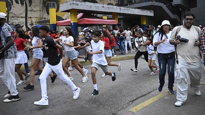 People run into a street in Caracas. AFP