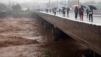 Indian people walk across the bridge over Tawi river which is closed for traffic amid flash floods and heavy rain in Jammu, the winter capital of Kashmir. Jaipal Singh/EPA