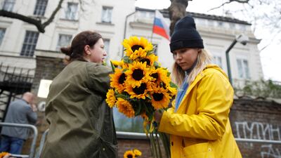 Anti-war protesters attach sunflowers to barriers in front of the Russian embassy. Reuters